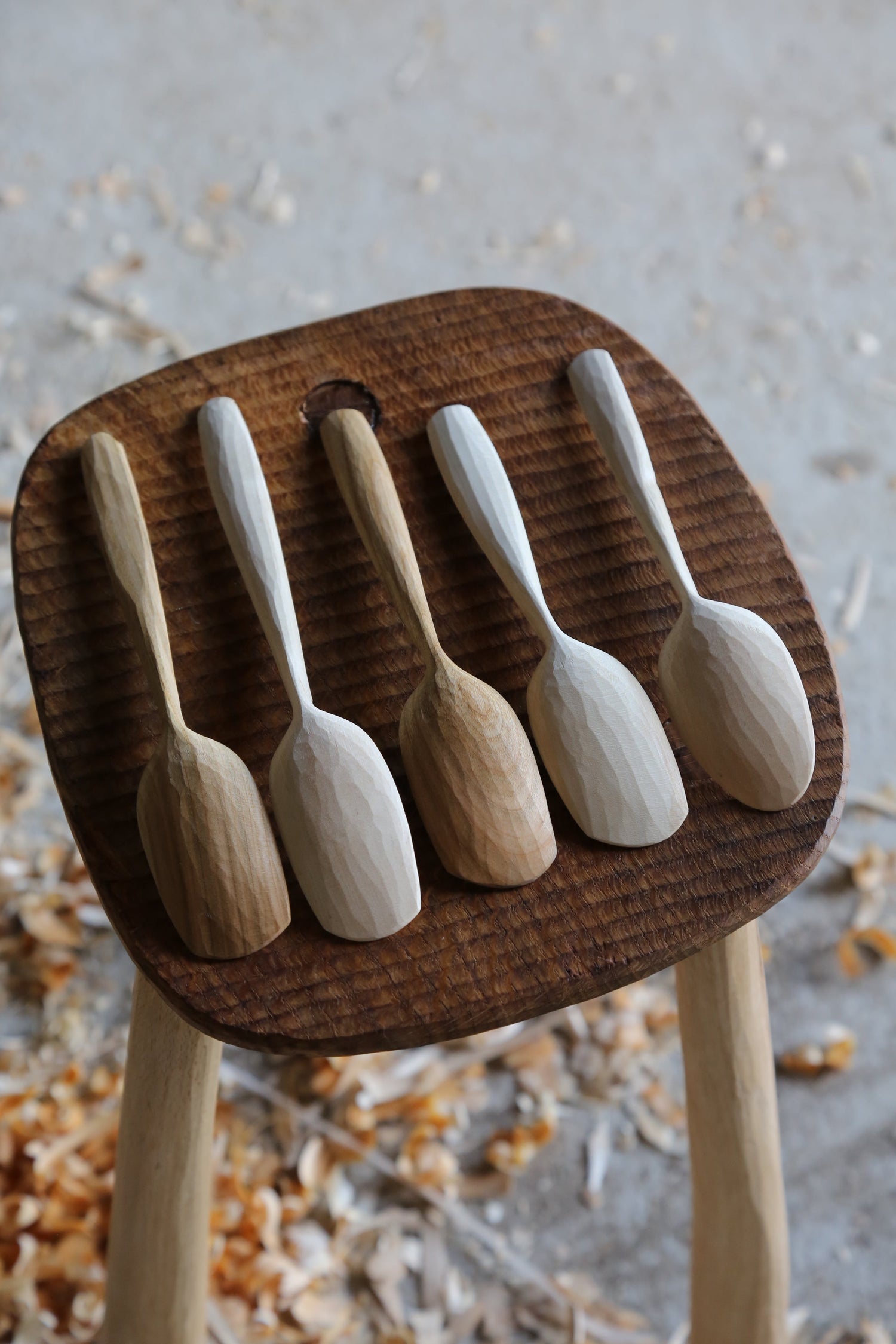5 wooden spoons sat on a textured oak stool