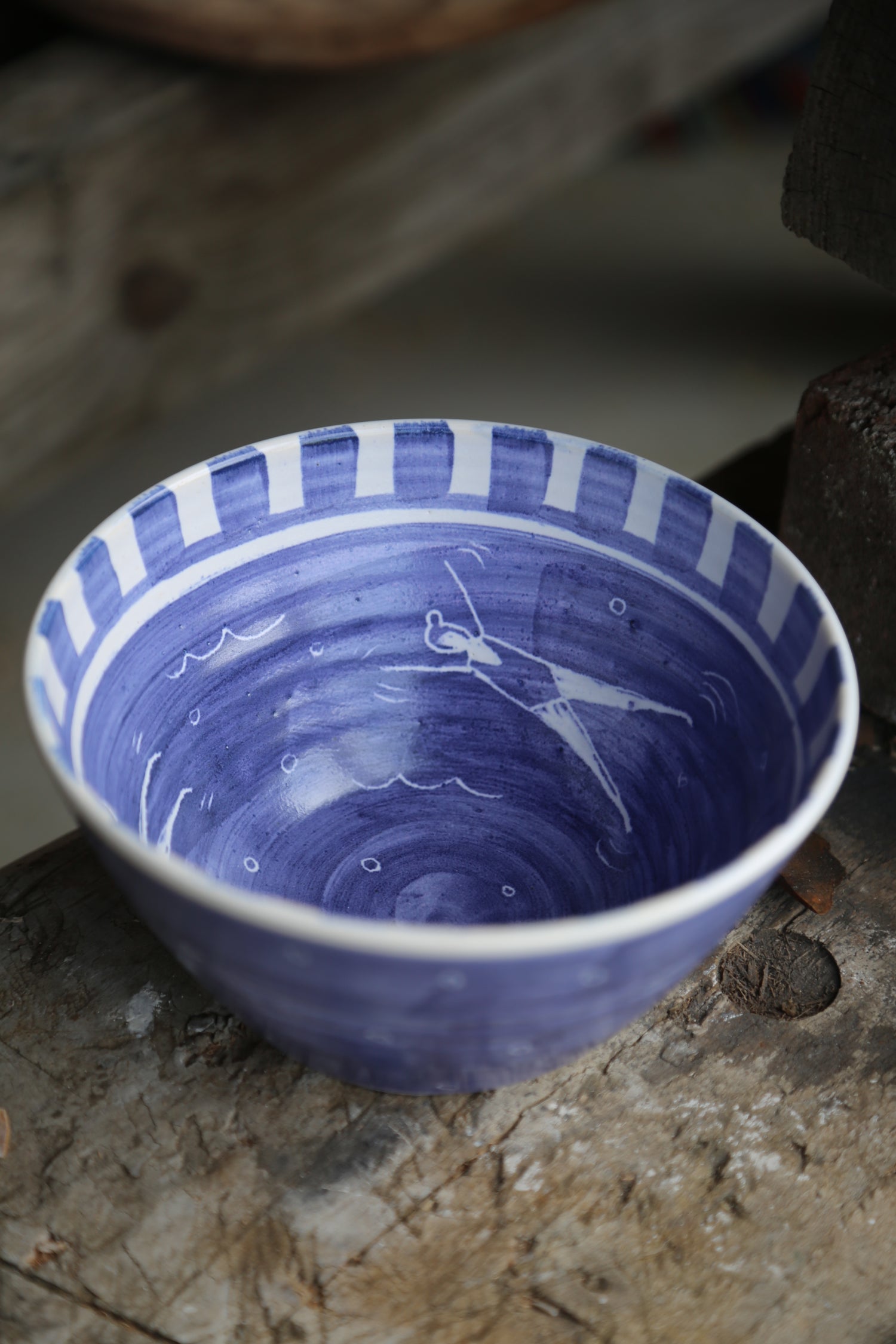 Wheel thrown stoneware bowl in blue and white with little swimming people on the inside 