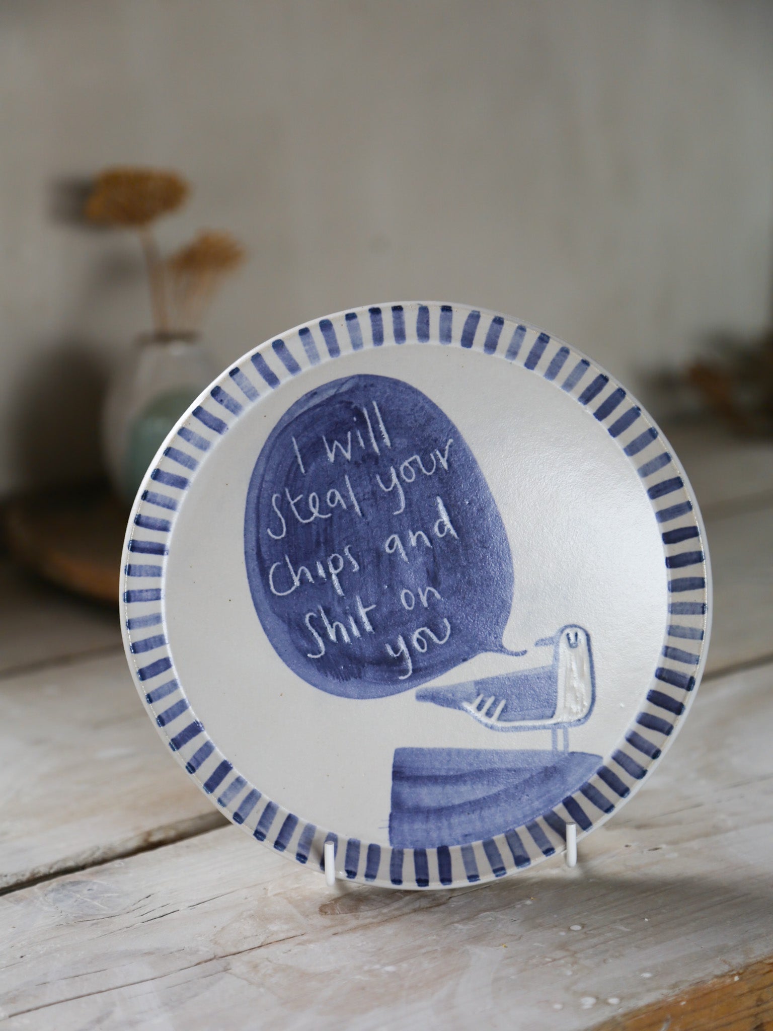 Decorative plate with blue design featuring a seagull saying "I will steal your chips and shit on you"